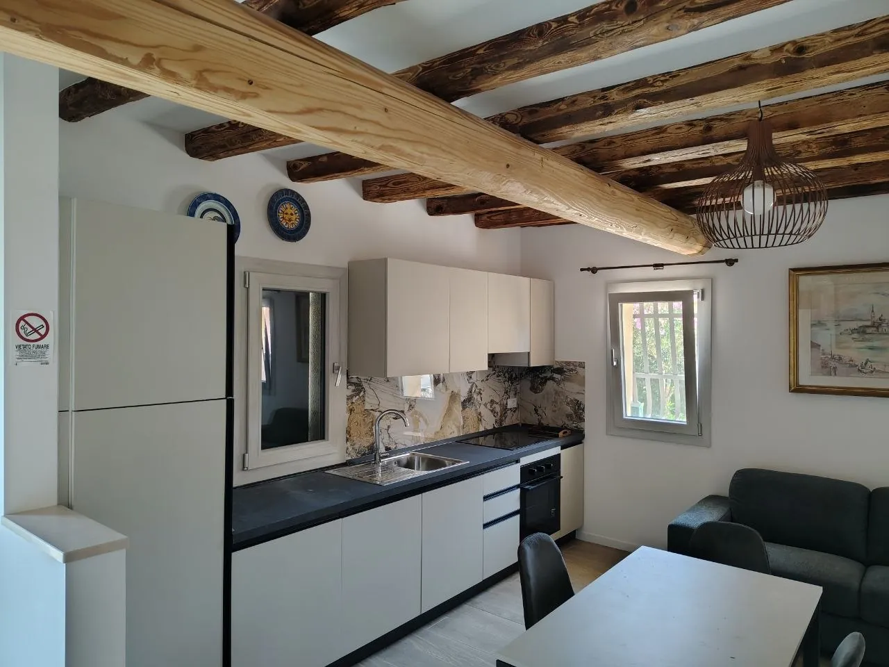 Cucina attrezzata e zona giorno luminosa con travi di legno